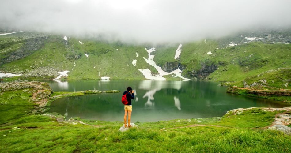 Photographer with backpack standing on Balea lake.